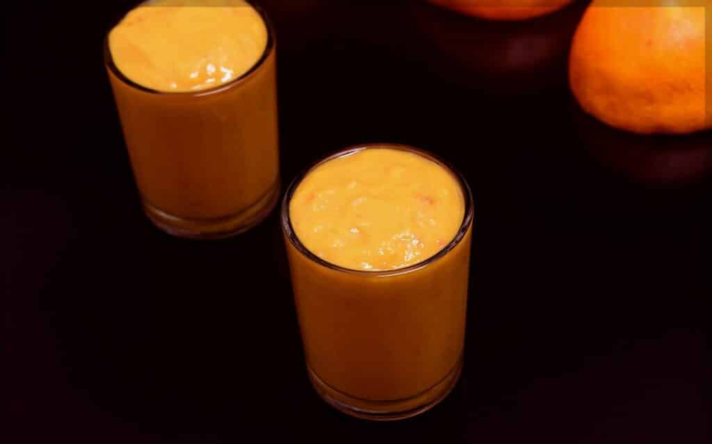 Vegetable smoothie with orange in jars.