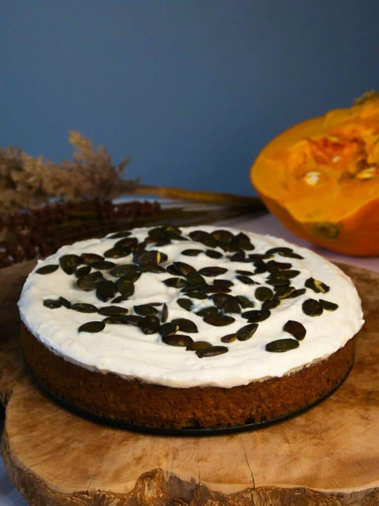 Pumpkin pie with vegan frosting, decorated with pumpkin seeds.