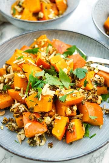 Baked pumpkin with feta, nuts and herbs on a plate.