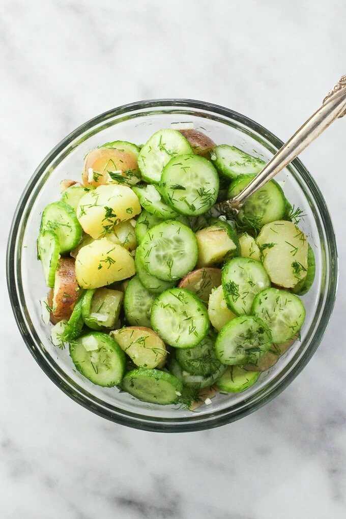 Potato-cucumber salad in a salad bowl with a spoon.