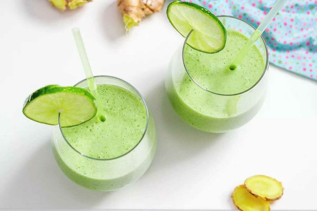Smoothie with cucumber, ginger, avocado, lime and baby spinach in glasses with straws and a slice of cucumber.