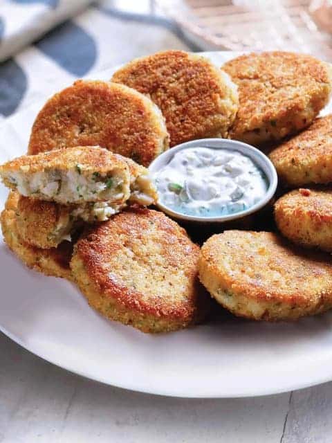 Fish cakes on a plate served with a dollop of seasoned mayonnaise.