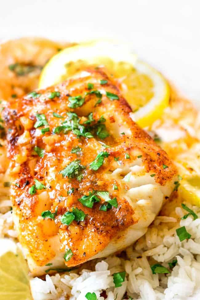 Cod in a garlic butter sauce served with rice and a slice of lemon.