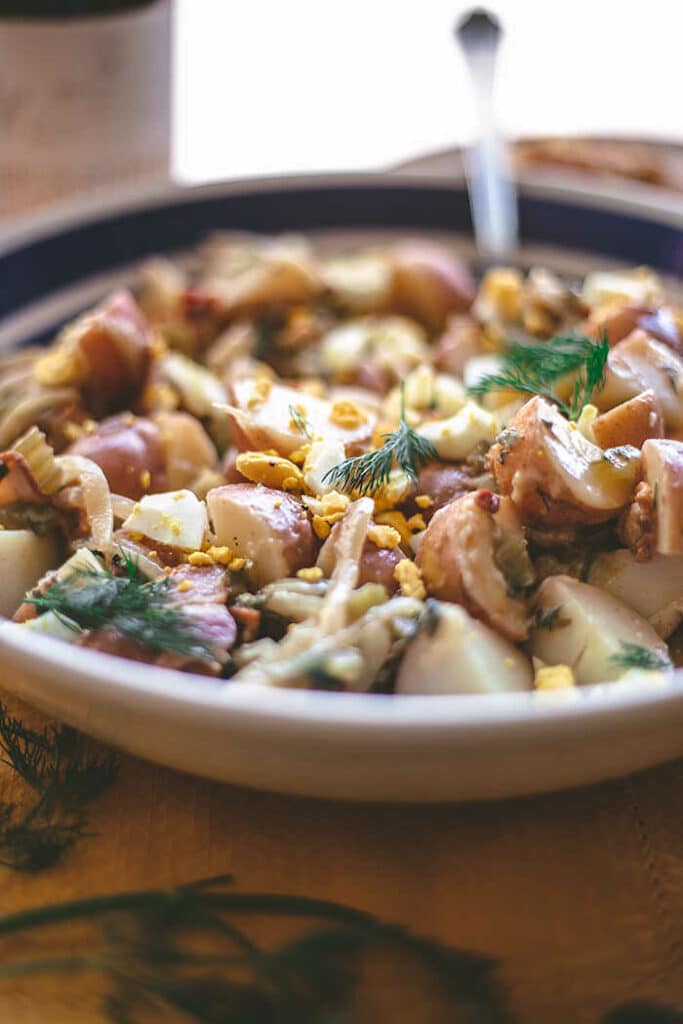 Salát z brambor, vajec a bylinek v míse.