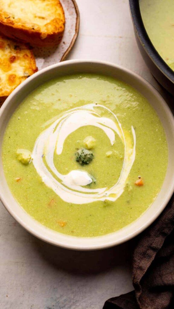 Zeleninová polévka v hlubokém talíři, ozdobená smetanou.