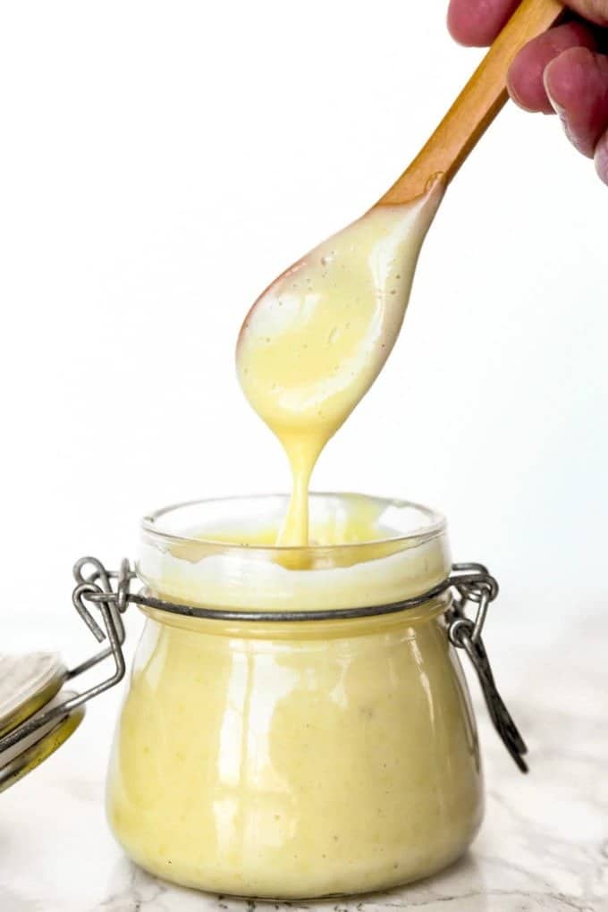 Mayonnaise with dashi powder in a glass, scooped with a wooden spoon.