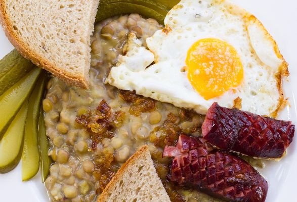 Lentils served with ox eye, sausage, bread and pickle.