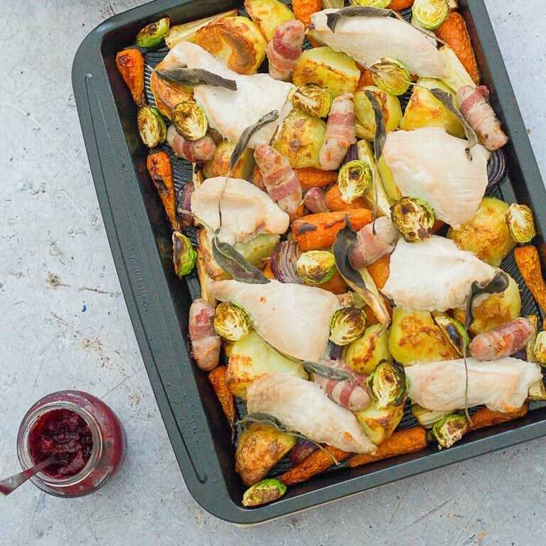 Roasted turkey slices with vegetables on a baking sheet.