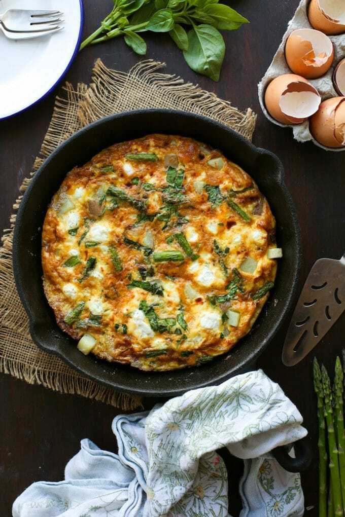 Potato frittata with asparagus, goat cheese and basil in a pan.