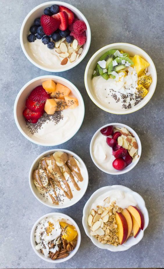 Bowls full of creamy yogurt with granola, fruit and other delicious ingredients.