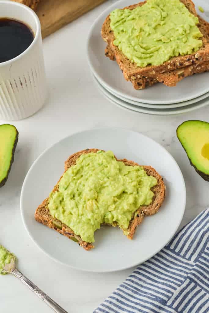 Slices of bread on a plate smeared with avocado dip.