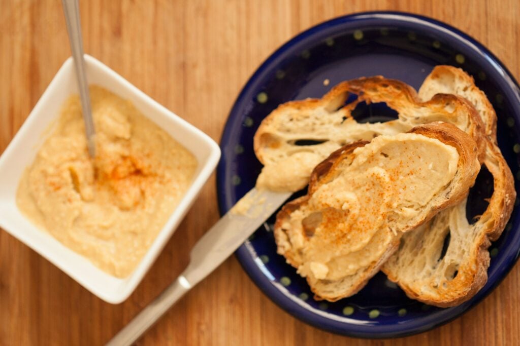 A plate with slices of bread and a knife, and a bowl with paprika dip is placed next to it.