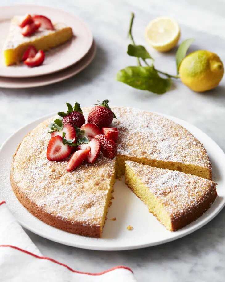Almond flour cake on a plate, decorated with fresh strawberries.