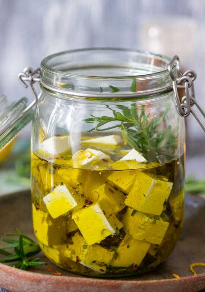 Feta naložená v olivovom oleji s rozmarínom, citrónovou kôrou a chilli v pohári.