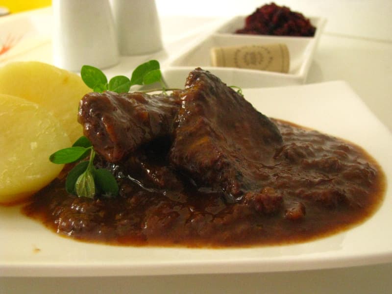 Beef with cranberry sauce and potatoes on a plate.