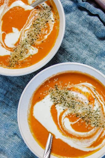 Tomaten-Kokos-Suppe voller Gewürze, serviert auf 2 Tellern.