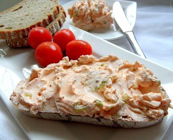 Cottage cheese dip spread on bread and served on a plate with fresh tomatoes and more bread.