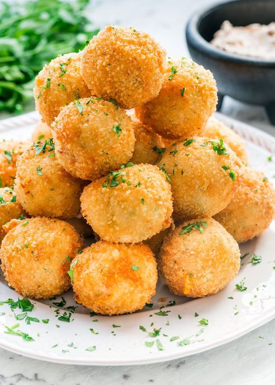 A pyramid of croquettes sprinkled with chives and filled with a fine mixture.