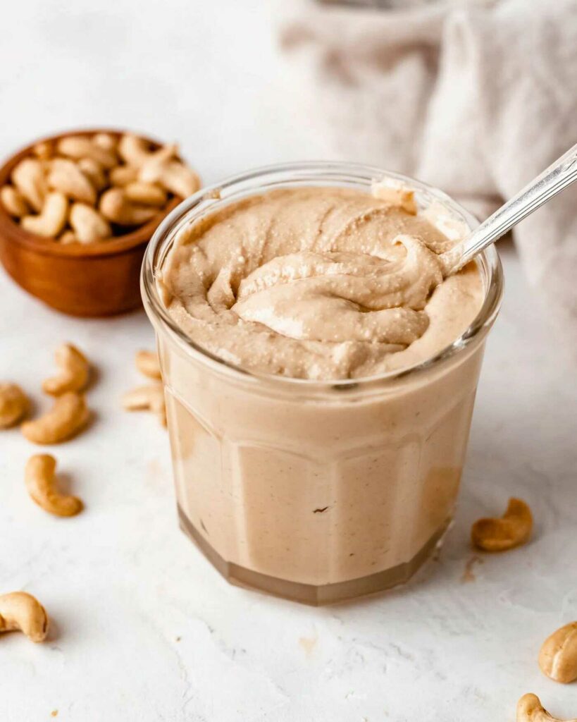 Cashew butter in a jar with a spoon.