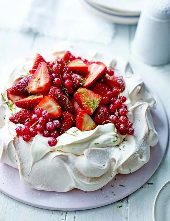 Fluffy egg white cake decorated with strawberries and currants.