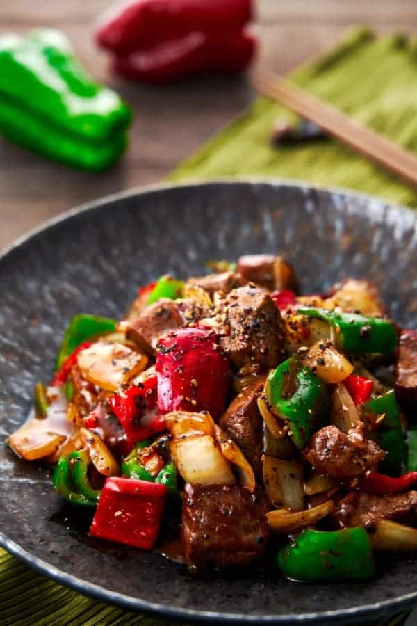 A stir-fried dish of beef, onions and peppers seasoned with oyster sauce and lots of black pepper on a plate.