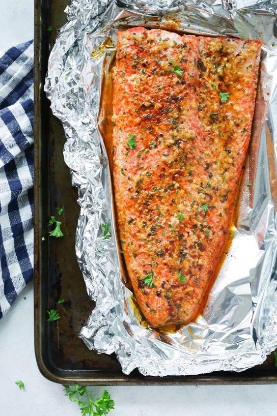 A large salmon fillet baked in foil seasoned with herbs and lemon.