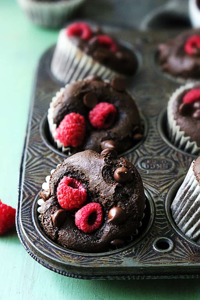 Muffiny s mléčnou čokoládou a sladkými čerstvými malinami ve formě na muffiny.