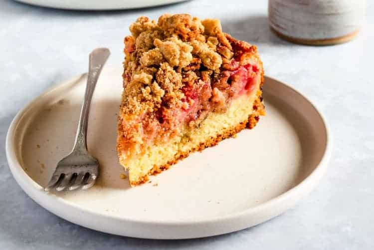 Jahodovo-rebarborový koláč s drobenkou na talířku s vidličkou.
