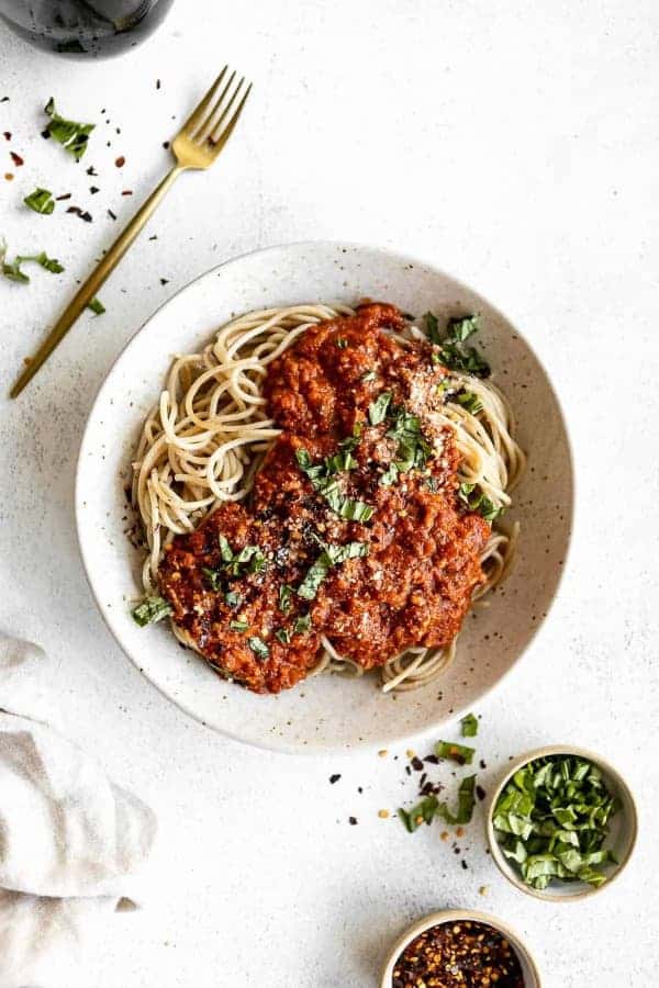 Špagety s rajčatovou omáčkou na talíři s vedle položenou vidličkou.