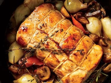 Vepřové maso svázané kuchyňským provázkem s cibulkami, žampiony a bylinkami.