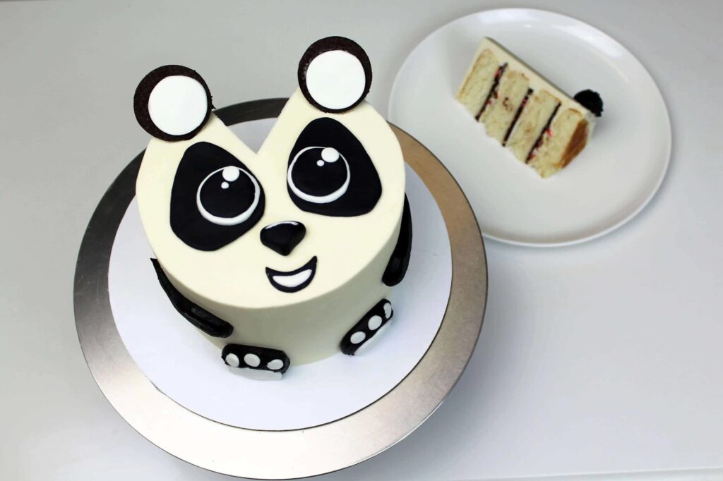 Vanilkový panda dort máslovým krémem, čokoládovou ganache, posypky a fondánem na talíři.