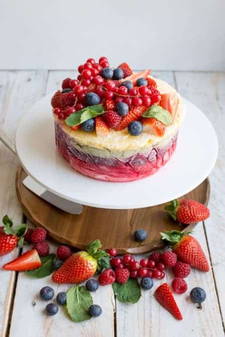 Ledový dort z čerstvého ovoce a jogurtu na talíři. Kolem je rozsypané čerstvé ovoce.