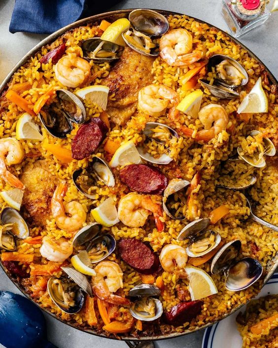 Krásně šafránově zbarvená paella s kuřecím masem, klobásou a mořskými plody.